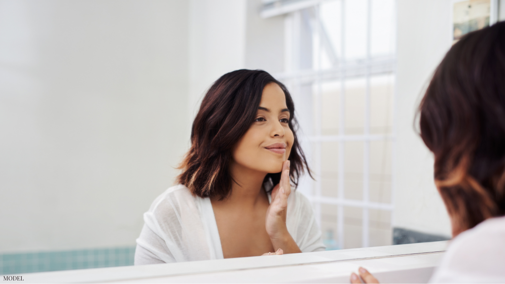 Woman looking in mirror after receiving injectable fillers