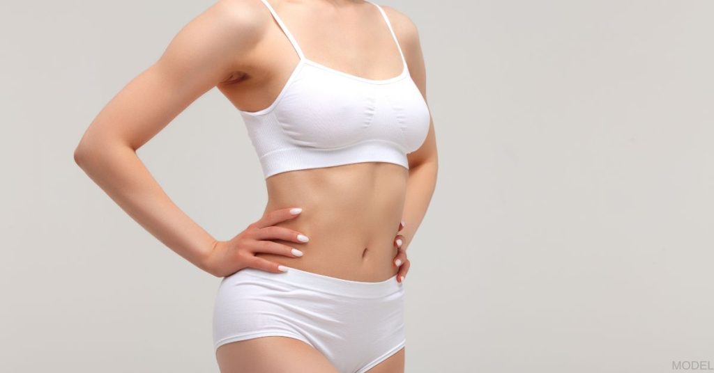 Woman in white undergarments with her hands on her hips. (MODEL)