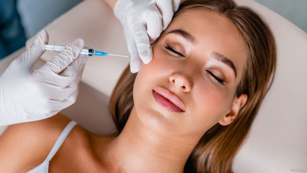 Woman laying down with eyes closed receiving injectable treatment (model)